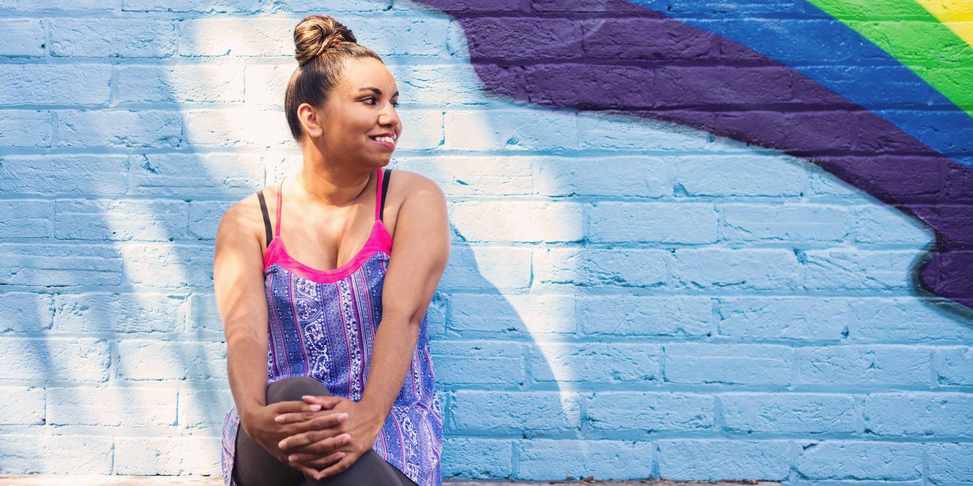 Image of girl sitting in front of a coloured wall.